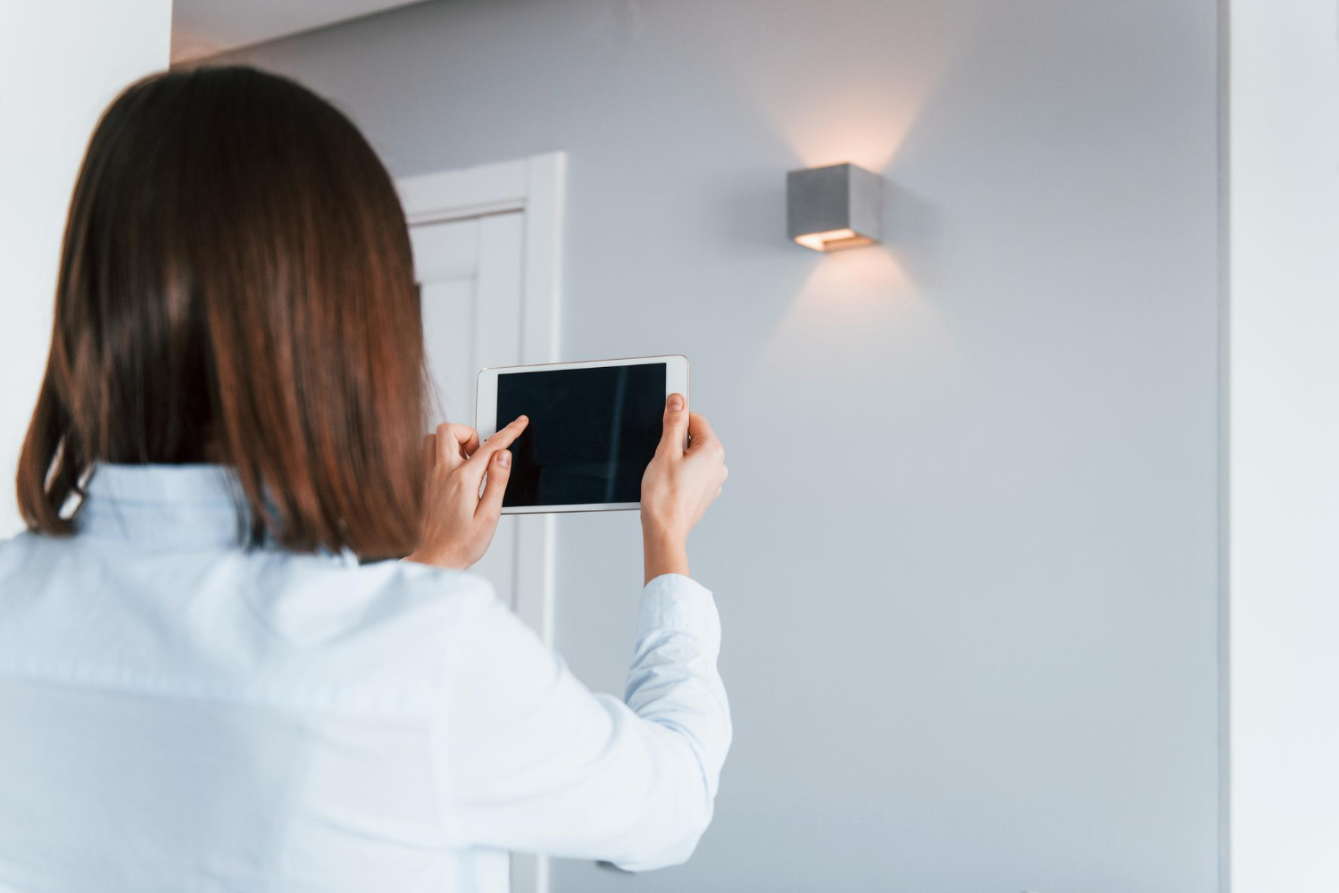donna controlla l'illuminazione della sua casa con un dispositivo digitale
